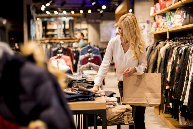 Young woman with shopping bags standing at the clothing store